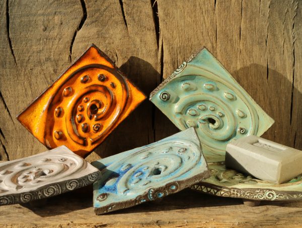 Rechteckige getöpferte Seifenschale in 5 Farben: orange, weiß, türkis, hellgrün und blau. Arrangiert mit einem Stück Seife.